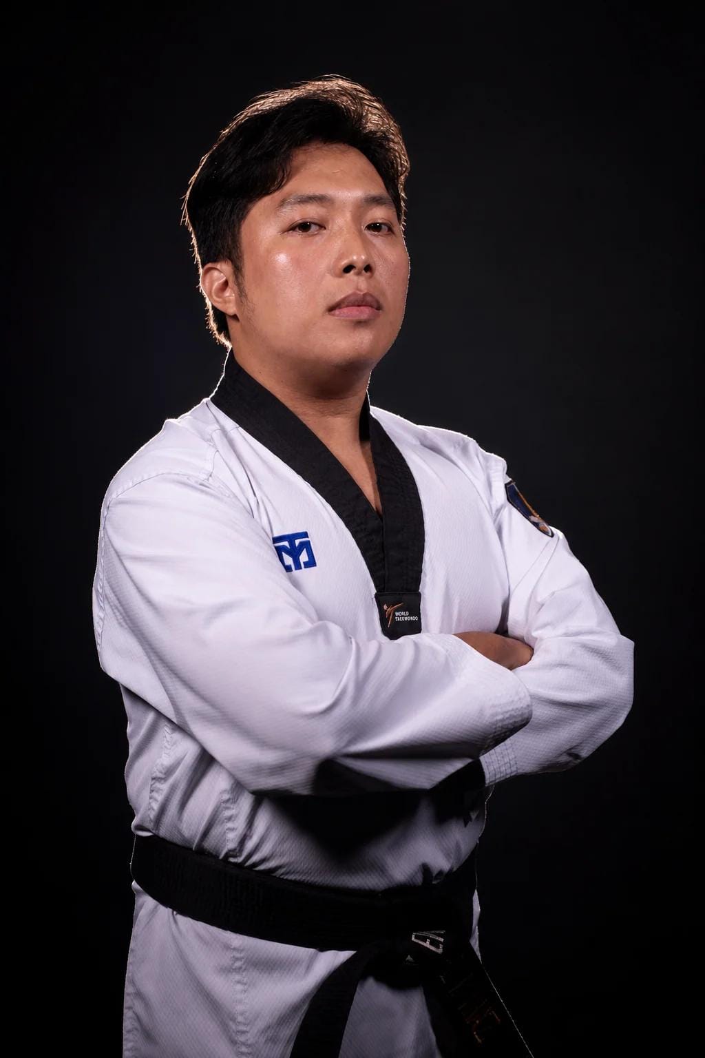 Coach Mark in a black-belt dobok, arms crossed