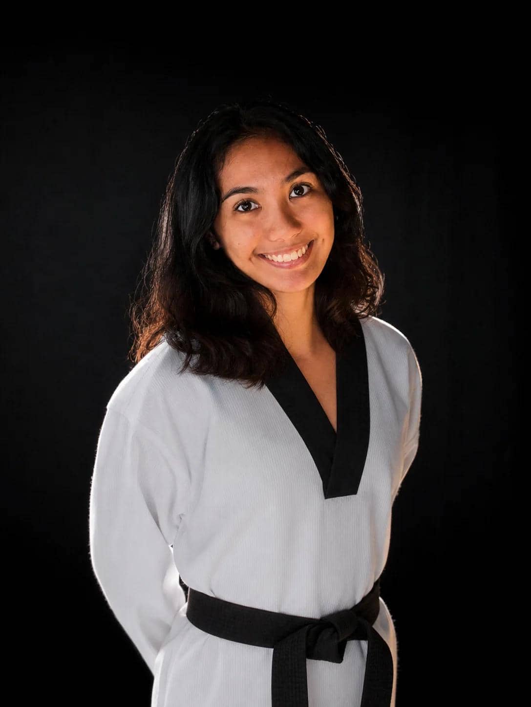 Coach Nica in a black-belt dobok, smiling