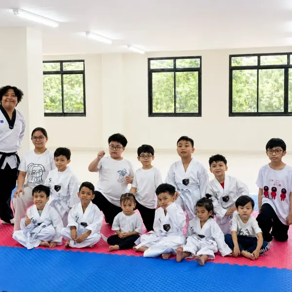 A black-belt coach with the Little Tigers class seated on the mat around him